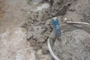 Fixing settled concrete - a bucket full of liquid concrete being mixed by a contractor before being poured.