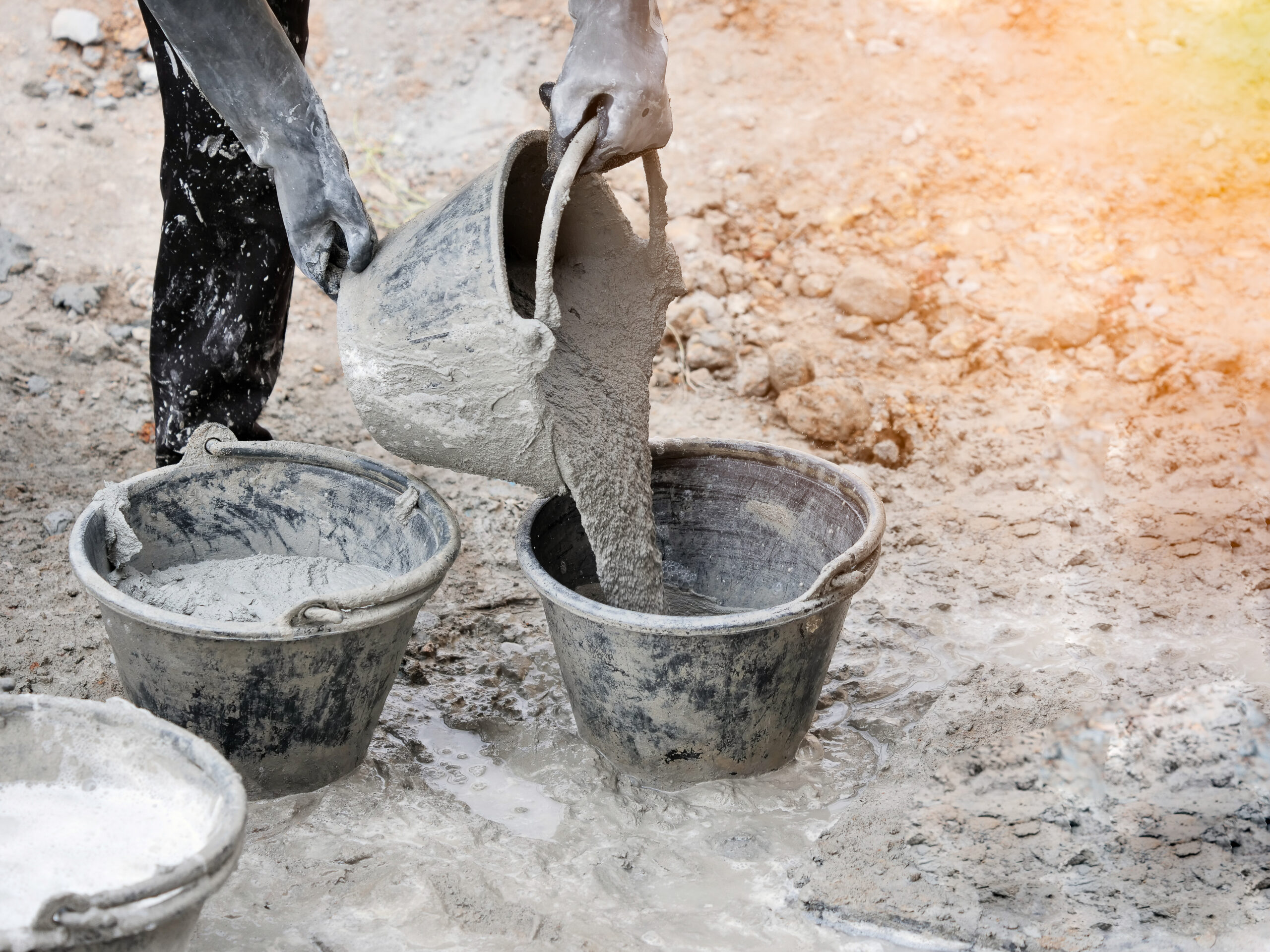 Settled Concrete - Image shows a construction worker pouring concrete in pails.
