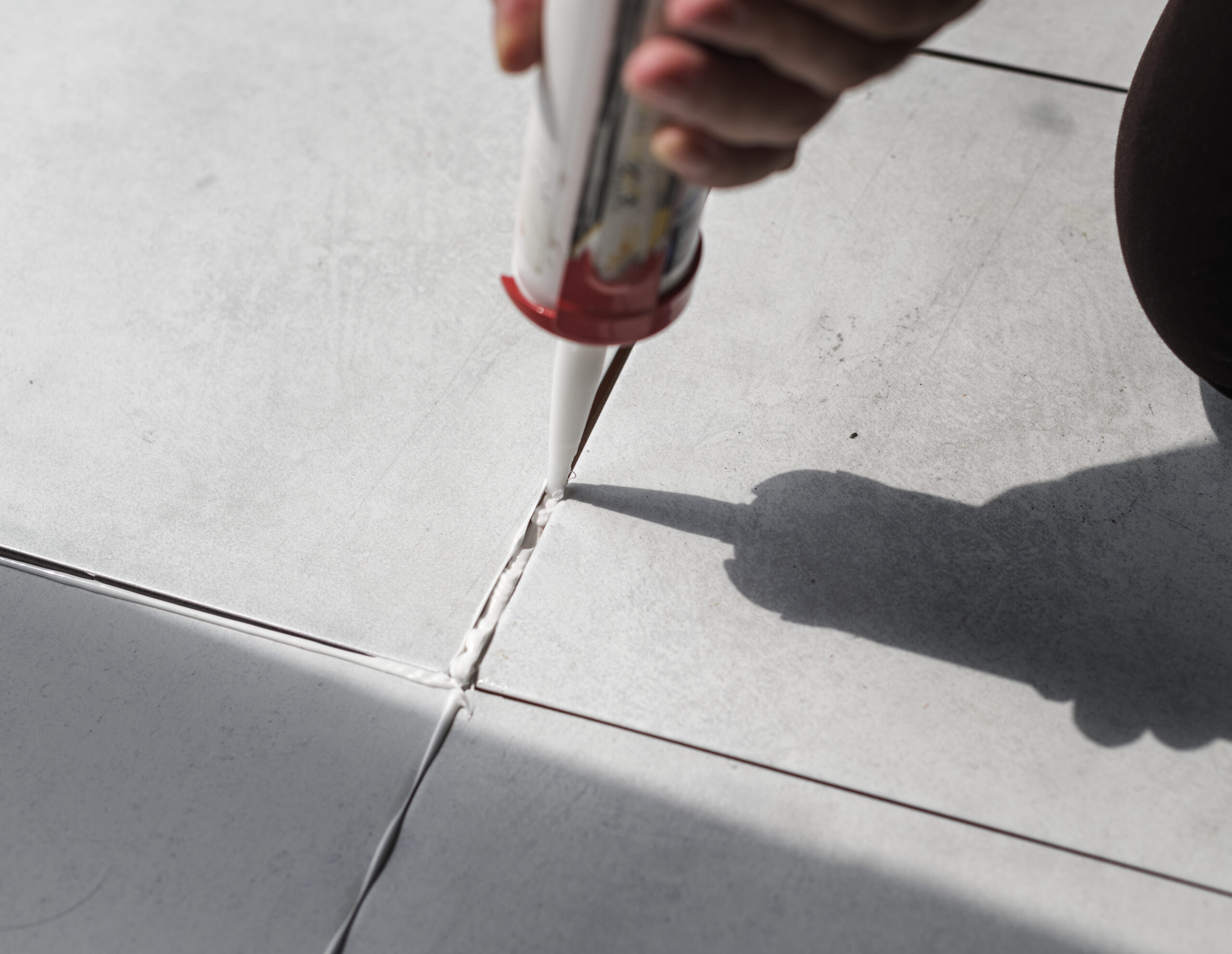 Concrete sealing in progress by a contractor wearing a white glove 
