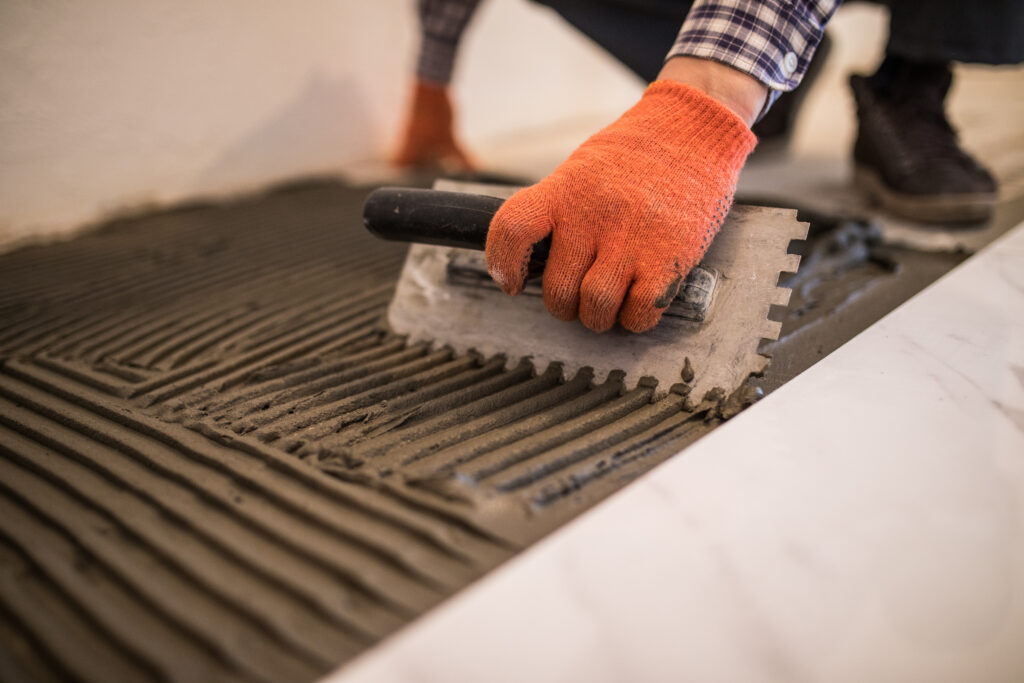 A man in Long Island trowelling the newly laid concrete slab to texture it into grooves.