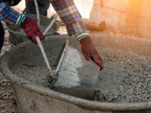 A construction worker collecting liquid concrete in a cement bucket to pour into a construction area.