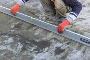 A contractor using a level to level the concrete.