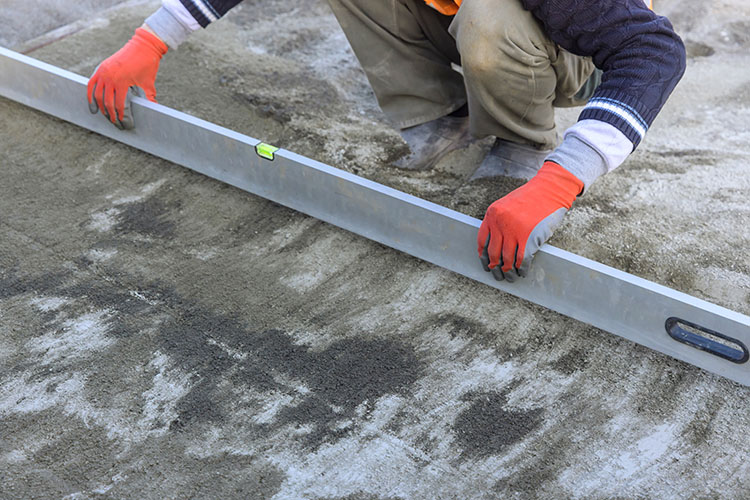 A contractor using a level to level the concrete.