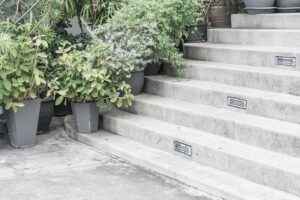 A beautiful series of concrete steps leading up to the entryway of a contemporary house lined with potted plants