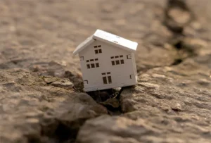 A house on a large cracked surface likely caused by ground subsidence.