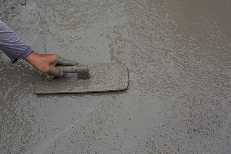 A professional contractor using a trowel to apply ultra high performance concrete to a building.