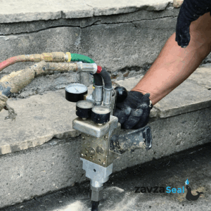 Polyjacking in progress with a machine that is pumping poly level form under the concrete slab